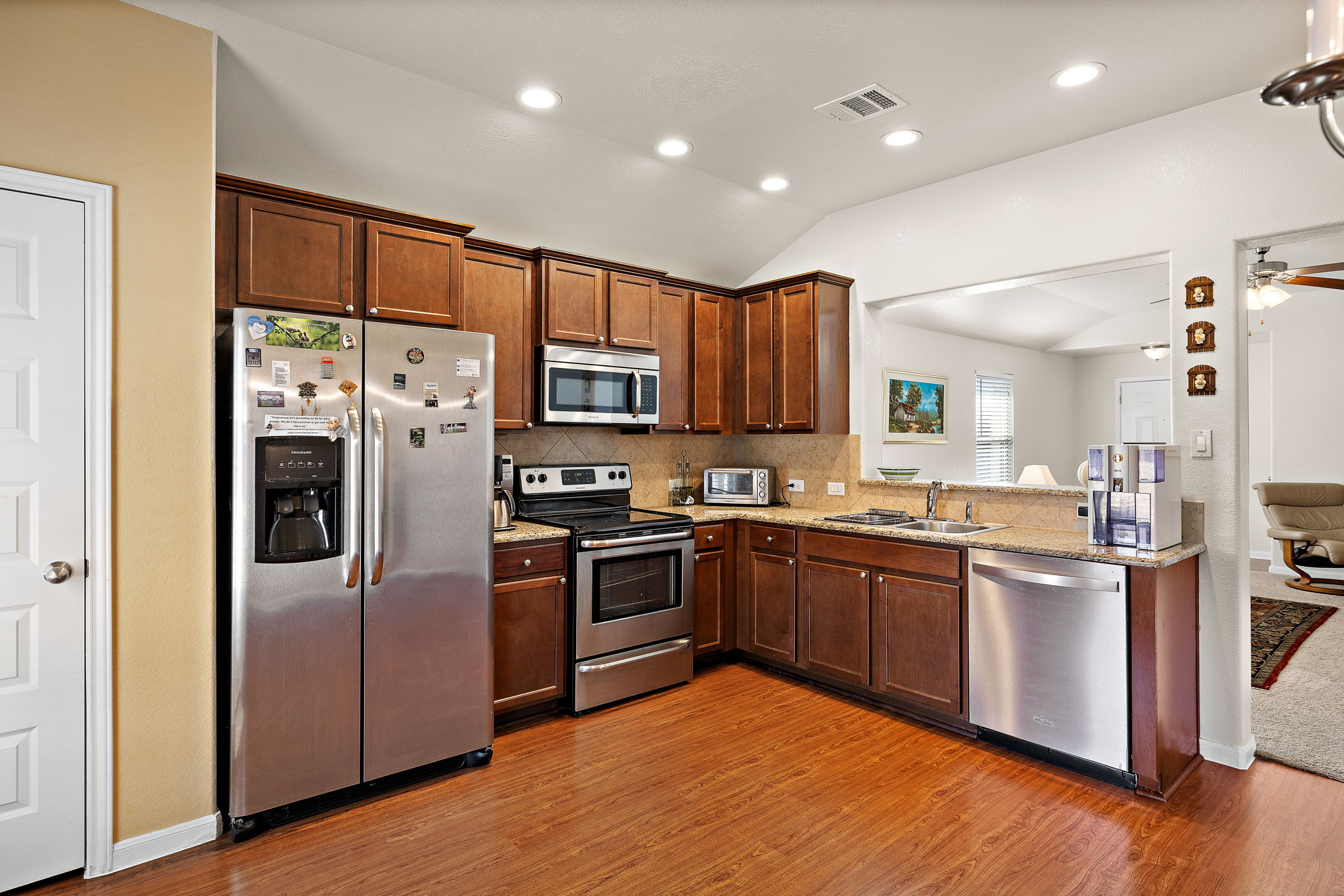 227 Avalanche Avenue Georgetown, TX 78626 - Photo 10 of 27 Kitchen featuring stainless steel appliances, vaulted ceiling, backsplash, light wood-type flooring, and granite countertops