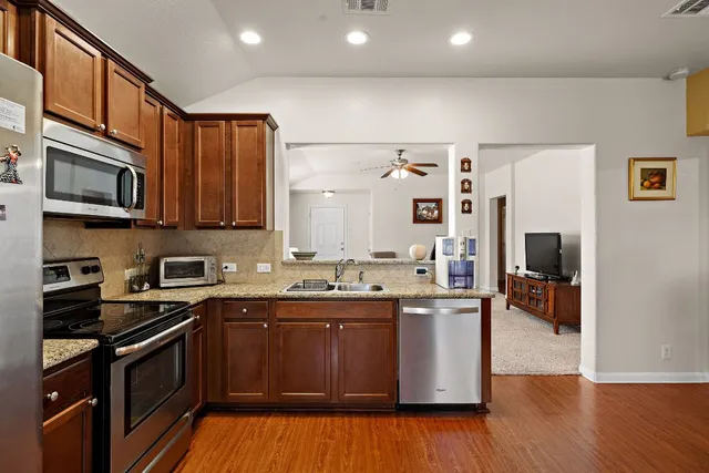 a kitchen with stainless steel appliances granite countertop a refrigerator a stove top oven a sink and dishwasher