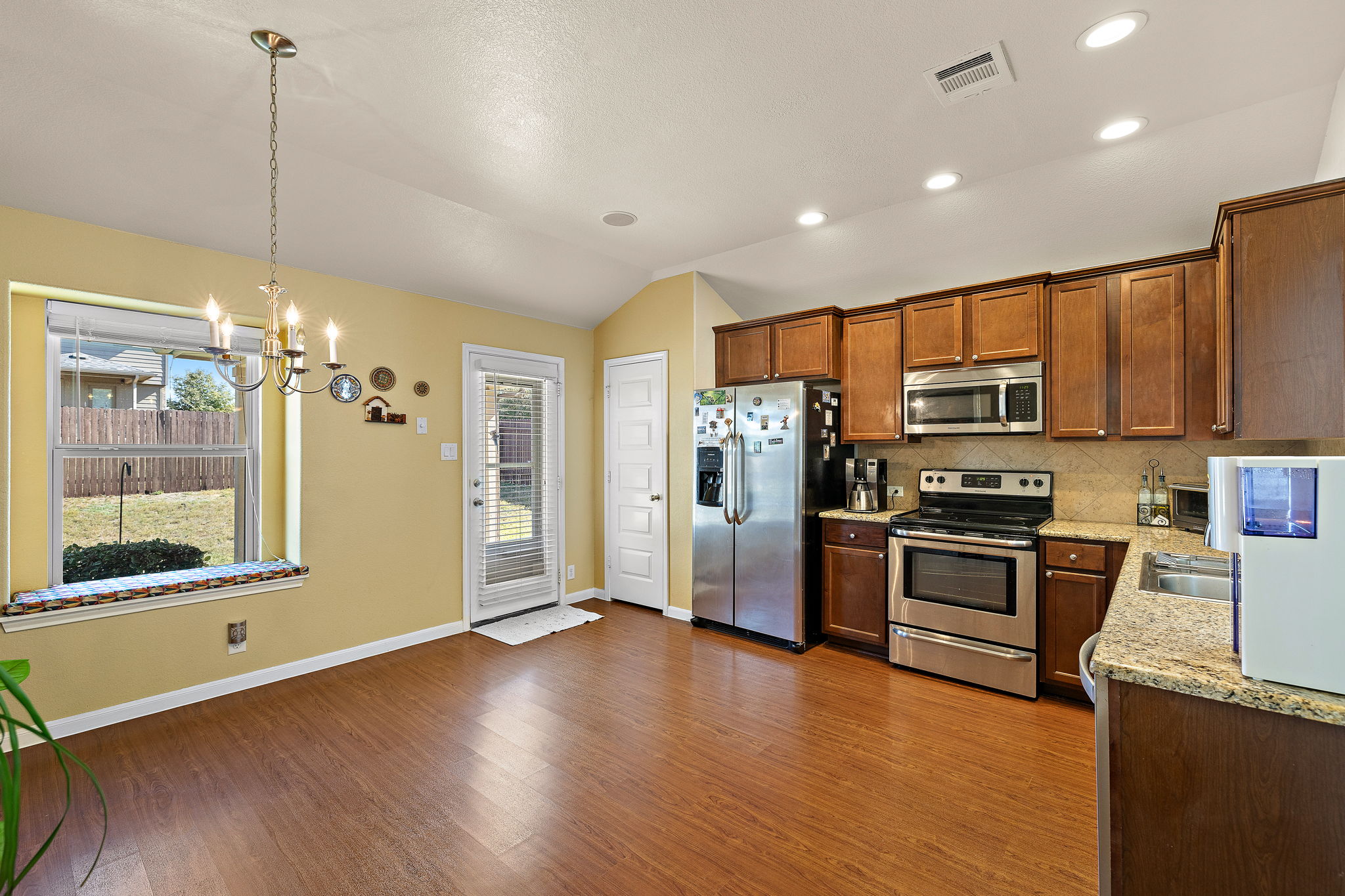 227 Avalanche Avenue Georgetown, TX 78626 - Photo 9 of 27 Kitchen featuring stainless steel appliances, decorative backsplash, light stone counters, healthy amount of natural light, and vaulted ceiling