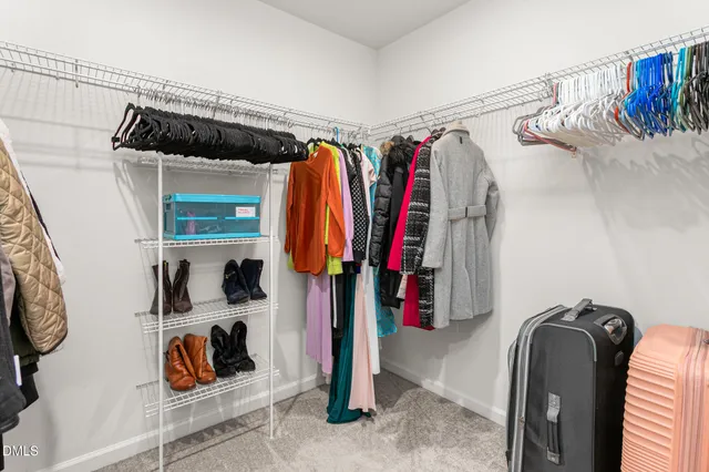a view of walk in closet with clothes and shoes
