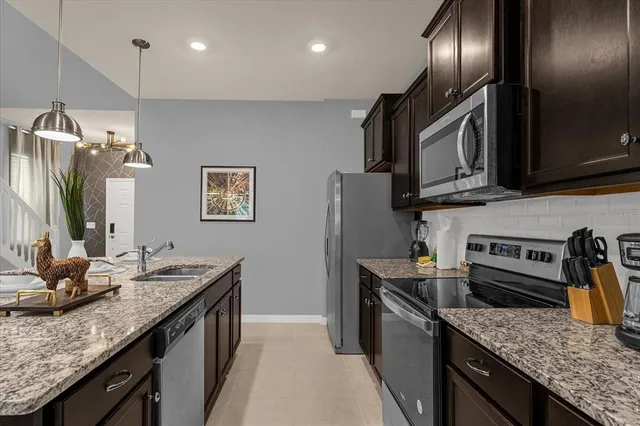 a kitchen with stainless steel appliances granite countertop a sink a stove a microwave cabinets and a dining table