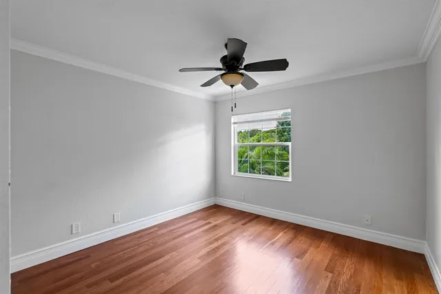 a view of empty room with wooden floor and fan