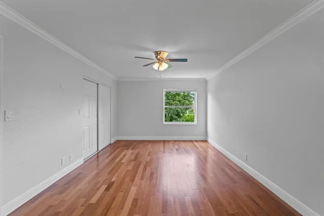 an empty room with wooden floor and a ceiling fan
