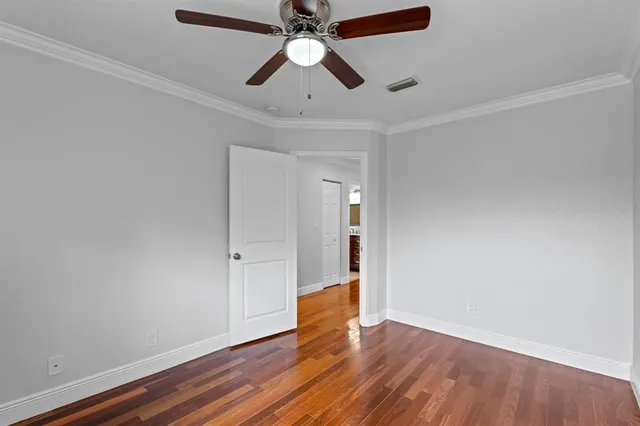 an empty room with wooden floor a ceiling fan and entryway