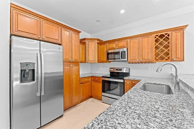 a kitchen with granite countertop stainless steel appliances a refrigerator stove top oven and sink