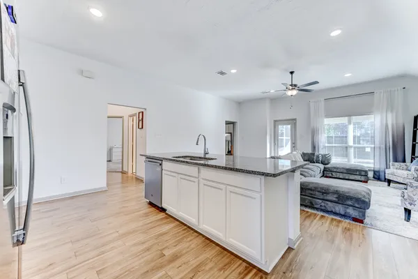 a large room with kitchen island granite countertop a sink and wooden floors