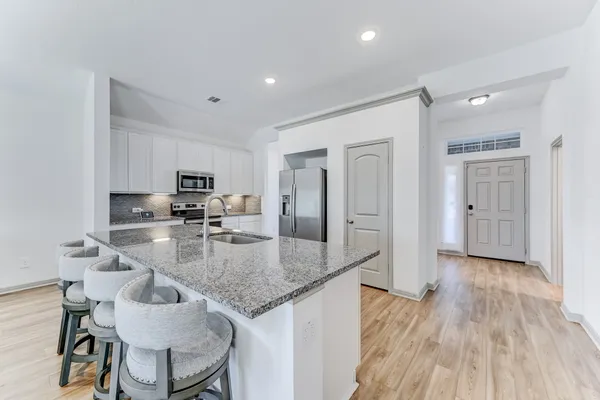 a kitchen with kitchen island granite countertop a sink cabinets and wooden floor