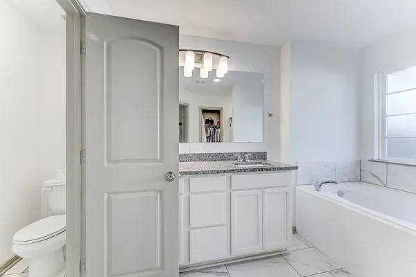a bathroom with a granite countertop sink mirror and a toilet