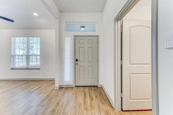 a view of an empty room with wooden floor and a window