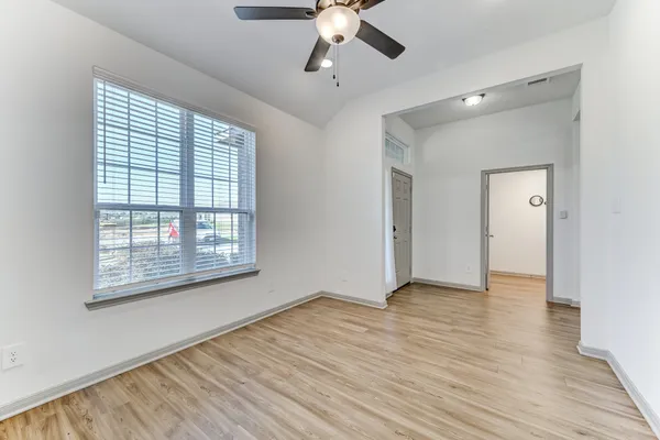 a view of an empty room with wooden floor and a window