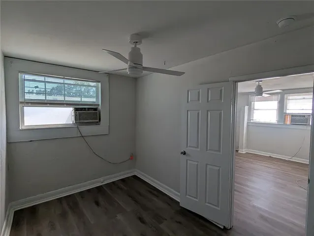 an empty room with wooden floor closet and windows