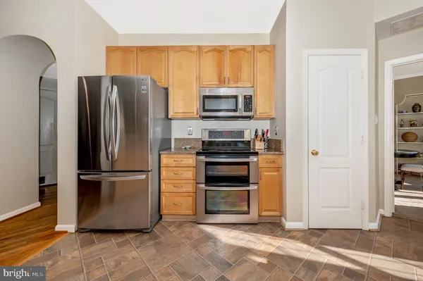 a kitchen with granite countertop a refrigerator and a stove top oven
