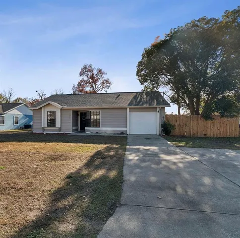 a view of a house with a yard and a large tree