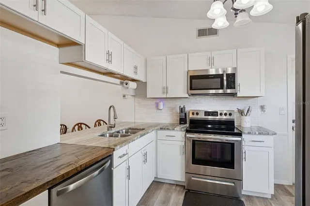 a kitchen with stainless steel appliances granite countertop a sink a stove a microwave and cabinets