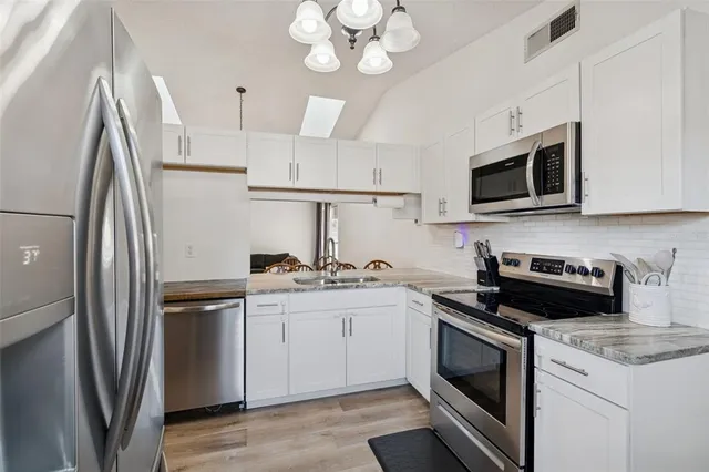 a kitchen with stainless steel appliances granite countertop a sink stove a refrigerator and a microwave