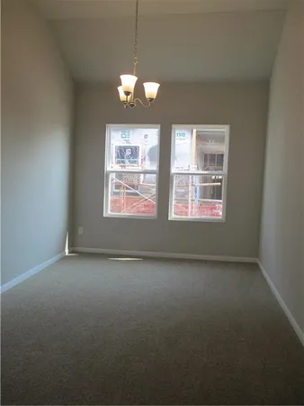 an empty room with chandelier fan and windows