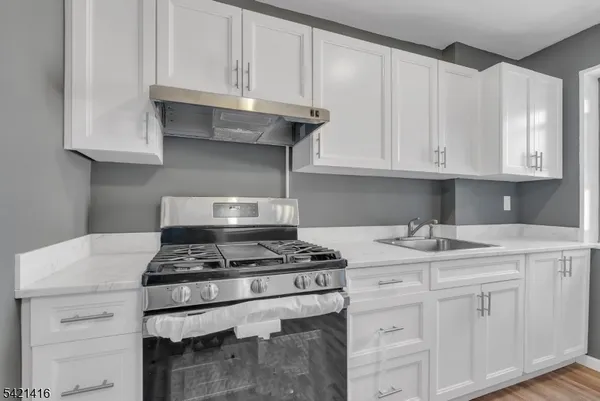 a kitchen with granite countertop a stove sink and cabinets