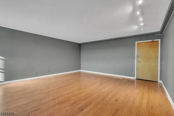 a view of an empty room with wooden floor and closet