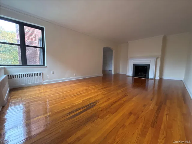 an empty room with wooden floor fireplace and windows