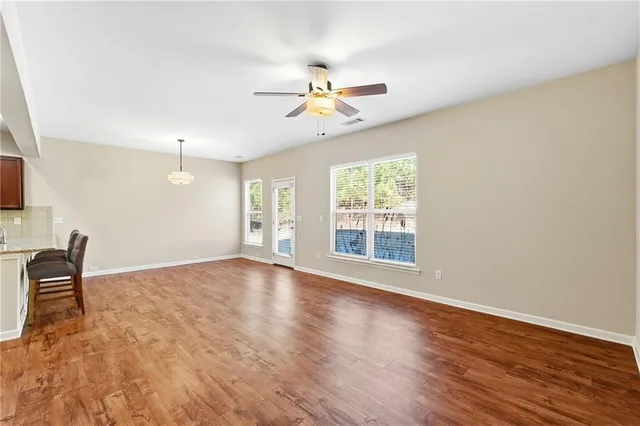 a view of an empty room with window and wooden floor