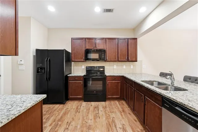 a kitchen with granite countertop wooden cabinets a refrigerator and a sink