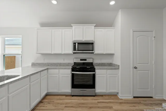 a kitchen with white cabinets and black appliances