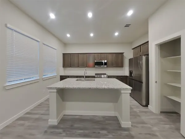 a view of kitchen with refrigerator stove sink and cabinets