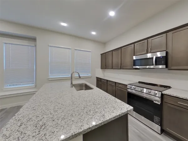 a kitchen with stainless steel appliances granite countertop wooden cabinets a stove a sink and a refrigerator