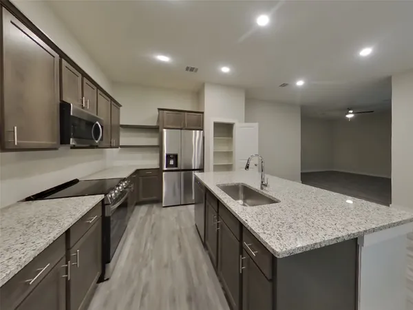 a kitchen with granite countertop kitchen island stainless steel appliances a sink stove top oven and refrigerator