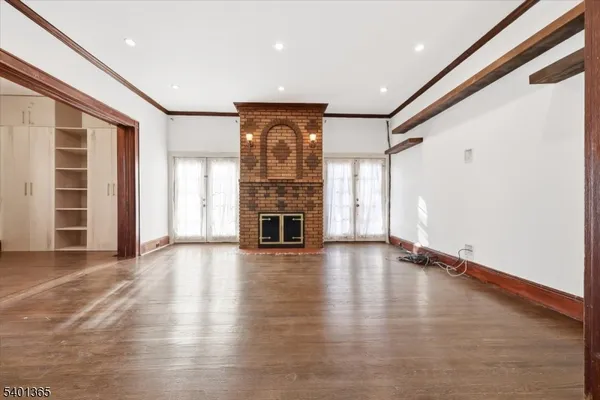 an empty room with wooden floor fireplace and windows