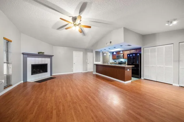 a view of an empty room with kitchen and a fireplace
