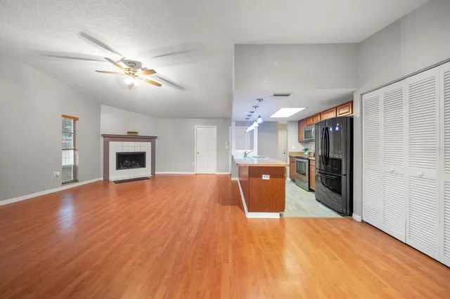 a view of empty room with wooden floor and kitchen view