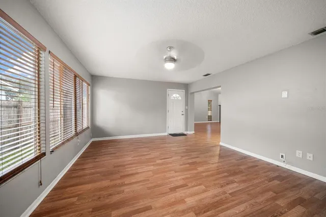 a view of an empty room with wooden floor and a window