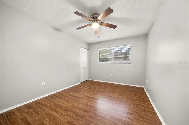 an empty room with wooden floor and ceiling fan