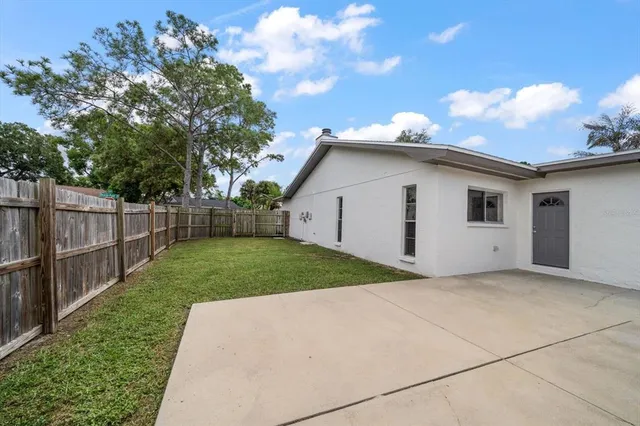 a view of backyard of house with wooden fence