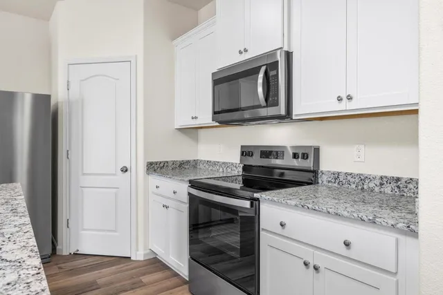 a kitchen with granite countertop white cabinets and stainless steel appliances