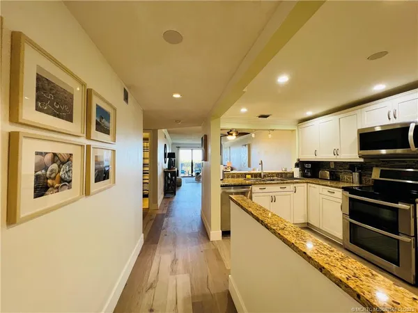 a large kitchen with stainless steel appliances granite countertop a large stove top oven a sink dishwasher a dining table and chairs with wooden floor