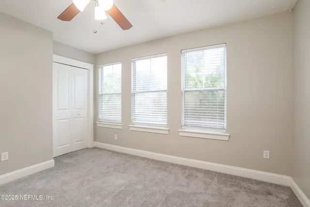 an empty room with wooden floor closet and windows