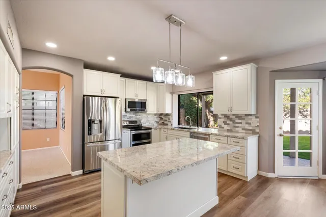 a kitchen with stainless steel appliances granite countertop a refrigerator a stove a sink and a microwave