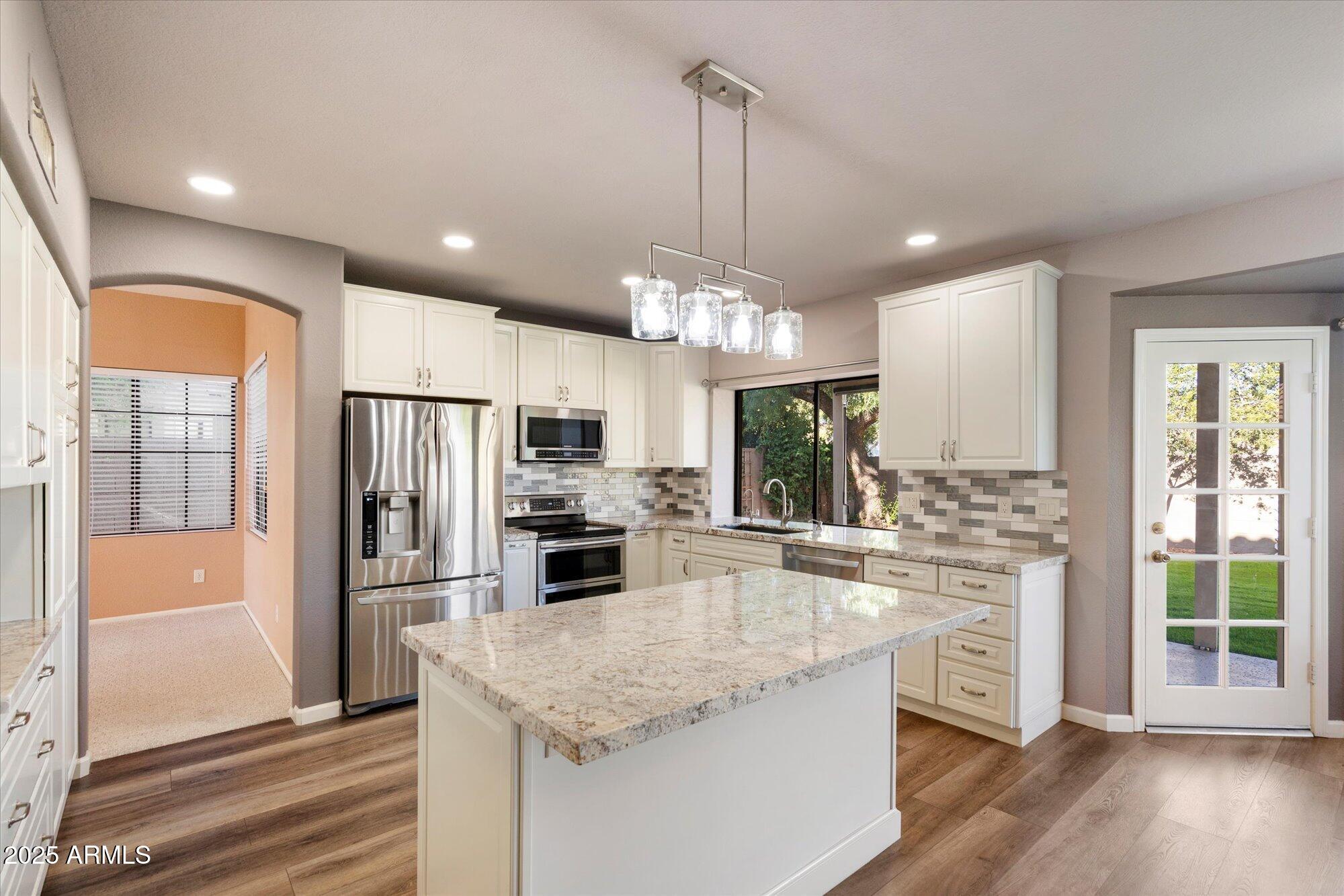 a kitchen with stainless steel appliances granite countertop a refrigerator a stove a sink and a microwave