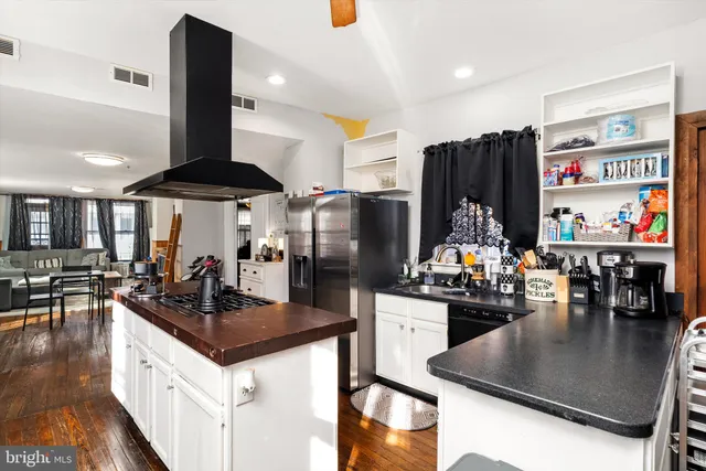 a kitchen with stainless steel appliances granite countertop a refrigerator a stove and a sink with wooden floor