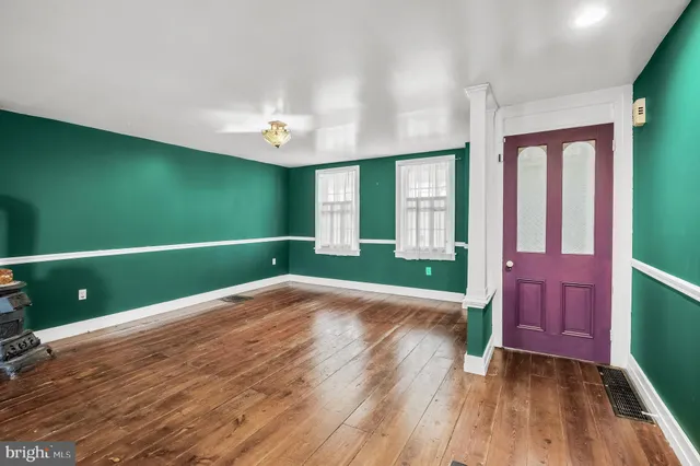 a view of an empty room with a window and wooden floor