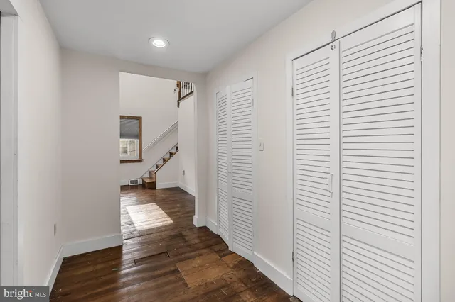 a view of a hallway with wooden floor and a bathroom