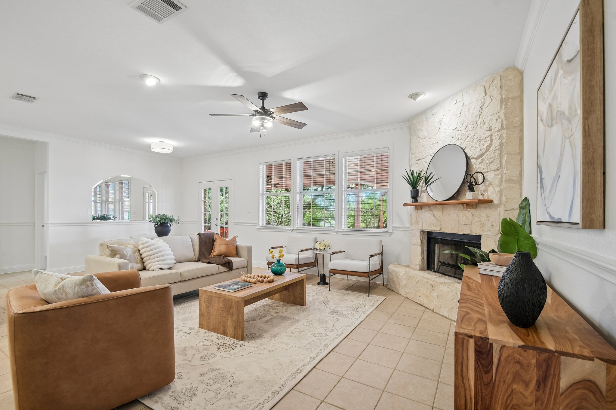 A comfortable living space featuring a tiled floor, stone fireplace, and ample natural light.