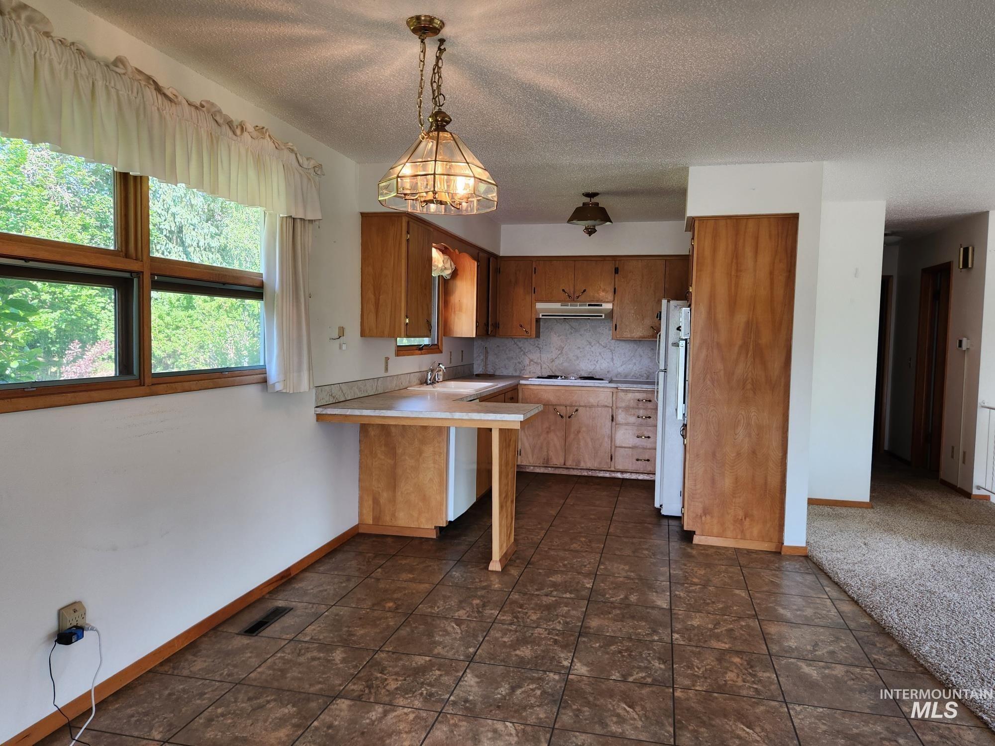 367 Woodland Road Kamiah, ID 83536 - Photo 7 of 49 Kitchen with light countertops, wood finish cabinets, freestanding refrigerator, backsplash, and pendant lighting