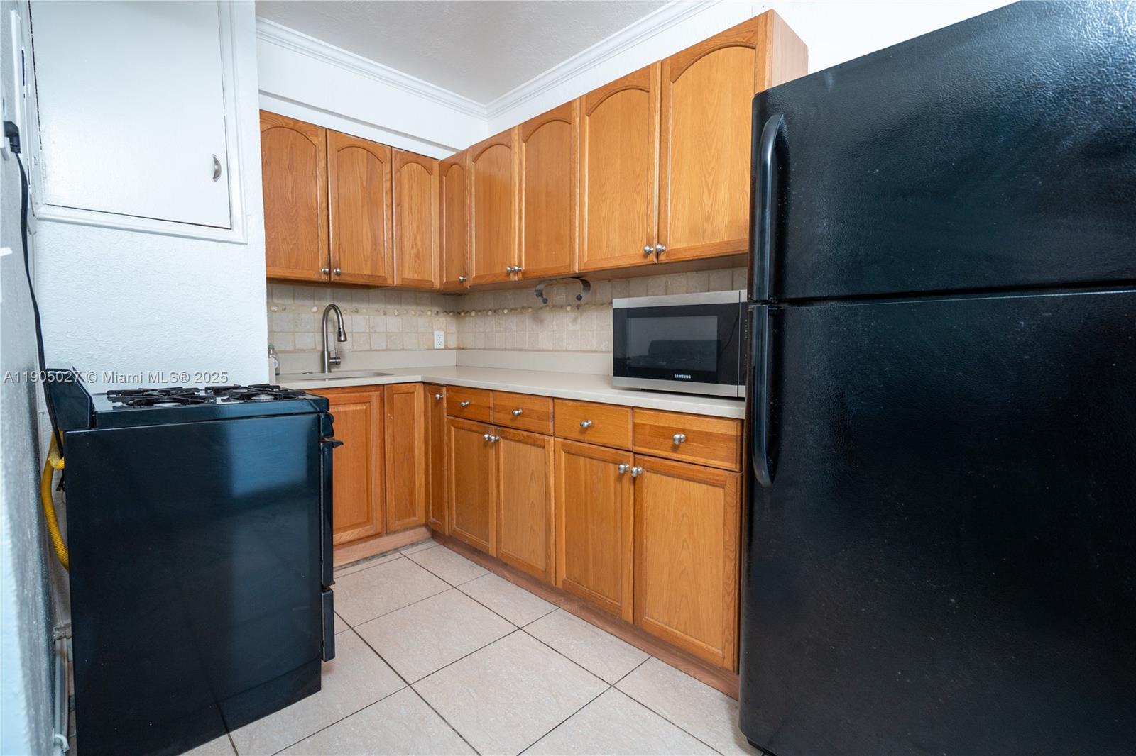 7435 Harding Avenue, Unit 204A Miami Beach, FL 33141 - Photo 4 of 14 a kitchen with a sink a refrigerator and cabinets