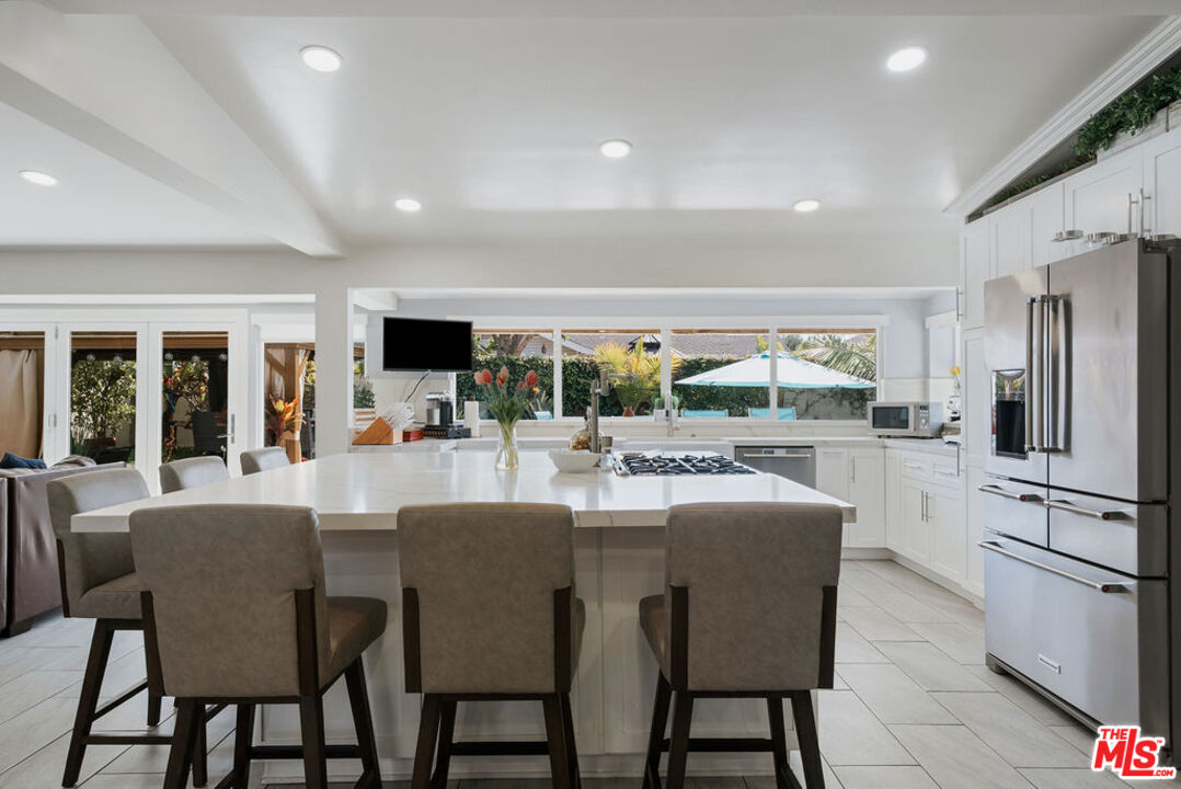 11332 Loch Lomond Road Los Alamitos, CA 90720 - Photo 13 of 55 a dining room with furniture a large window and a kitchen view
