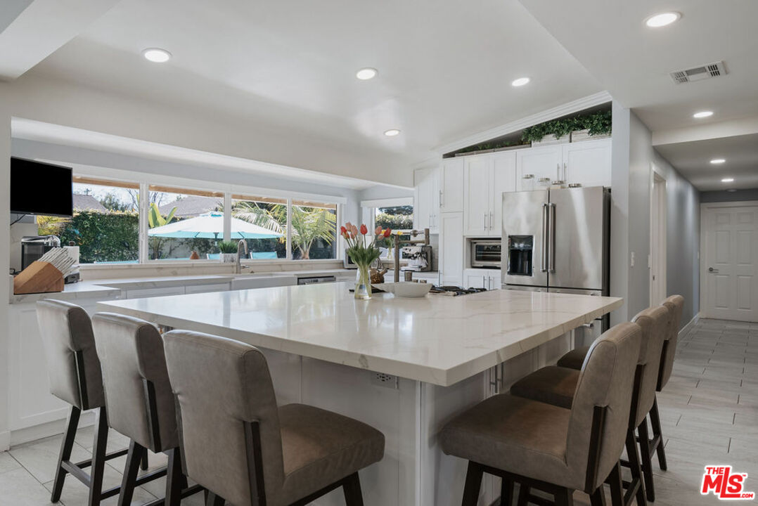 11332 Loch Lomond Road Los Alamitos, CA 90720 - Photo 15 of 55 a kitchen with stainless steel appliances granite countertop a table chairs and a refrigerator