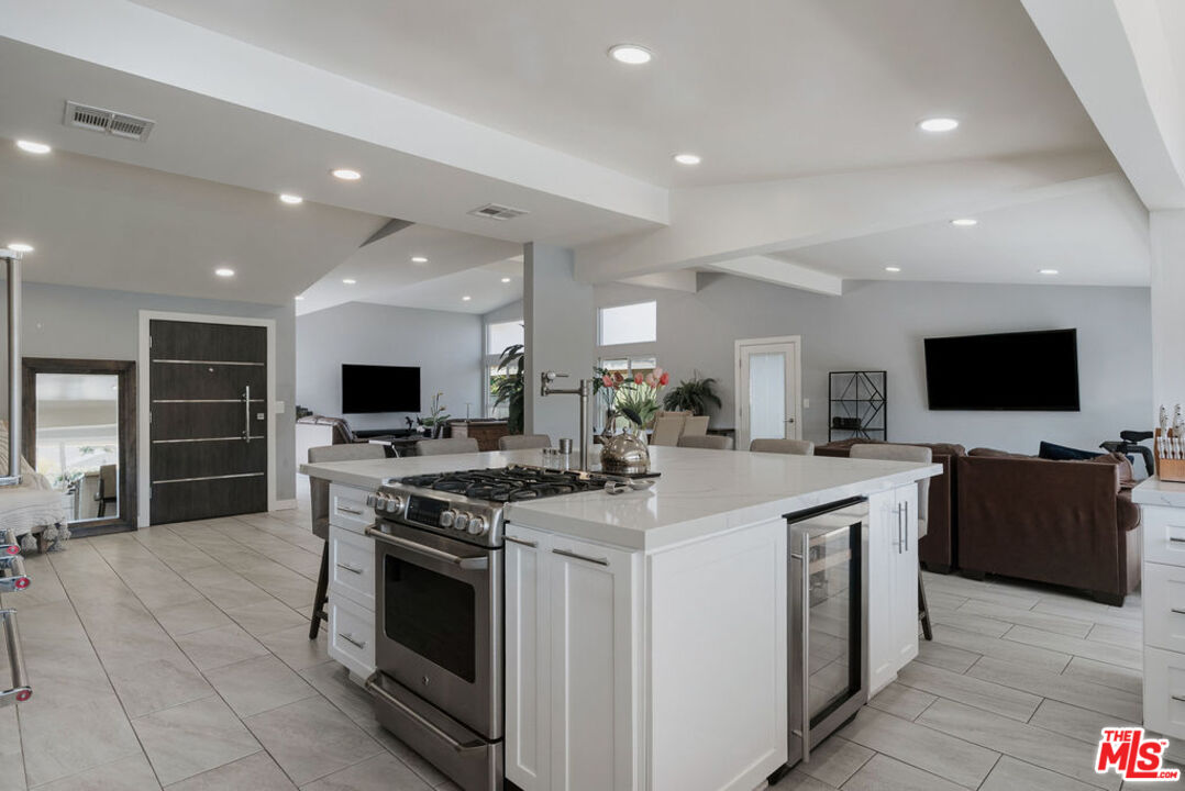 11332 Loch Lomond Road Los Alamitos, CA 90720 - Photo 21 of 55 a kitchen with stainless steel appliances kitchen island granite countertop a stove top oven a sink a dining table and chairs with wooden floor