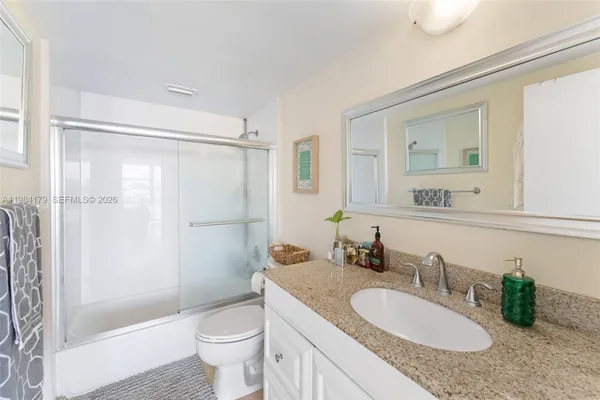 a bathroom with a granite countertop sink toilet and shower